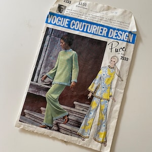 May include: Vintage Vogue Couturier Design sewing pattern featuring a design by Emilio Pucci of Italy. The pattern is for a two-piece outfit with a long-sleeved top and wide-legged pants. The pattern is printed on a white background with a blue and yellow illustration of the outfit.