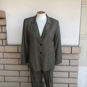 May include: A brown and beige plaid suit jacket and pants. The jacket has a single-breasted closure with three buttons and two flap pockets. The pants have a straight leg.