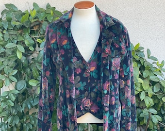 May include: A black velvet jacket with a floral print featuring pink, green, and yellow roses. The jacket has a collar and long sleeves.