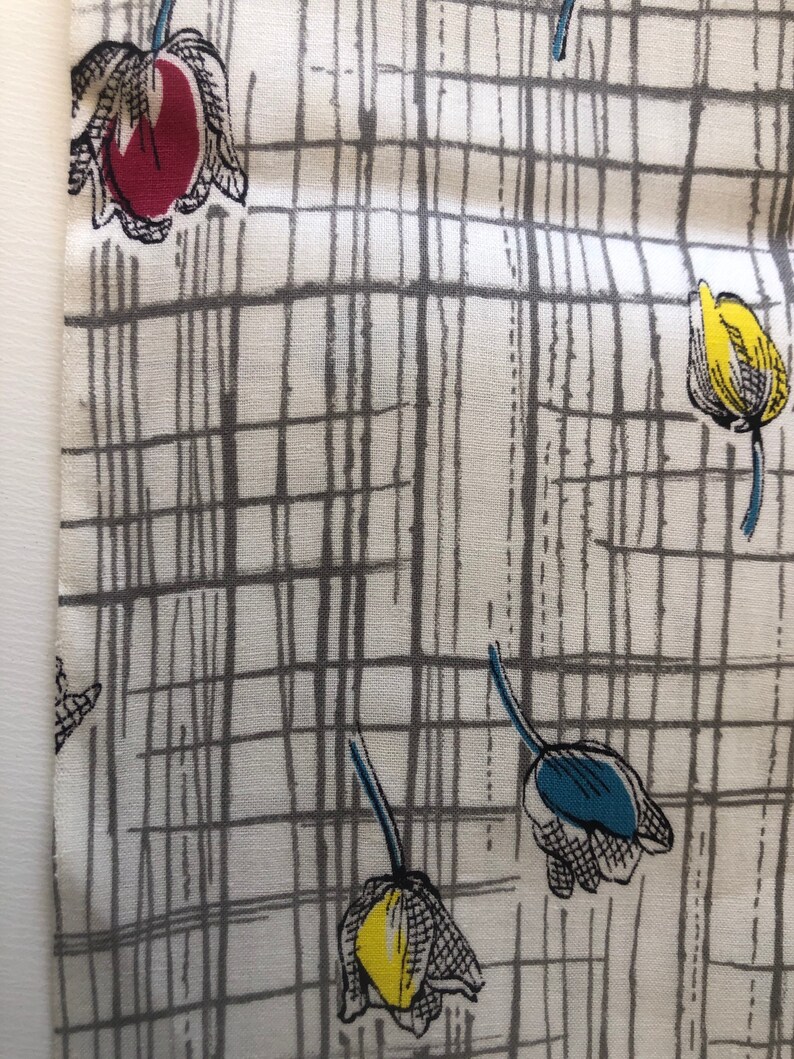 May include: White fabric with a gray grid pattern and colorful tulip illustrations. The tulips are red, yellow, and blue.