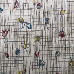 May include: A white fabric with a repeating pattern of stylized tulips in shades of red, yellow, blue, and gray. The tulips are arranged on a grid of thin black lines.