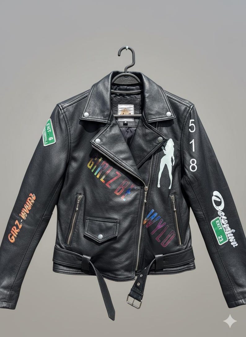 May include: Black leather jacket with a classic biker style, featuring a notched collar, asymmetrical zip closure, and a belted waist. The jacket is adorned with colorful graffiti-style text and a white silhouette graphic. Includes Exit 6, 23 and 9 signs.