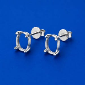 May include: A pair of silver-toned metal earring settings featuring an oval-shaped prong mounting designed to hold a gemstone. Each earring includes a post back and a circular disc backing, showcasing a polished metallic finish and four prongs.