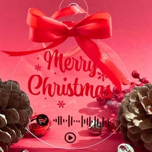 Könnte beinhalten: Ein klarer, kreisförmiger Weihnachtsschmuck mit dem Schriftzug "Merry Christmas" in roter Schrift. Der Schmuck hat eine rote Schleife oben und einen Spotify-Code unten. Der Hintergrund ist rot.