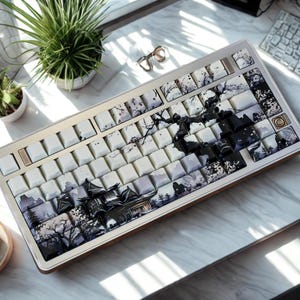 Może przedstawiać: Niestandardowa klawiatura mechaniczna z białymi klawiszami z czarno-szarym wzorem inspirowanym Japonią. Klawiatura ma drewnianą ramę i srebrną górną płytę. Klawisze przedstawiają krajobrazy, drzewa i sztukę abstrakcyjną.