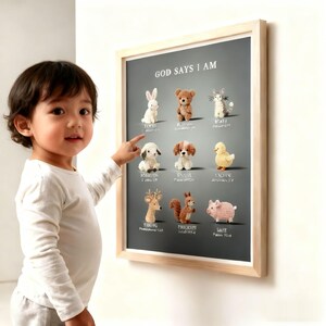 Könnte beinhalten: Ein gerahmter Druck mit dem Text "GOD SAYS I AM" und gehäkelten Tierfiguren, darunter ein Hase, ein Bär, eine Katze, ein Schäferhund, ein Welpe, eine Ente, ein Hirsch, ein Eichhörnchen und ein Schwein. Der Rahmen ist aus hellem Holz.