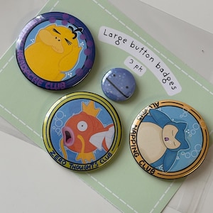 May include: Three circular button badges featuring cartoon characters and text on a light green backing card labelled Large button badges 3 pk. The badges depict a yellow character with the text HEADACHE CLUB, an orange fish with ZERO THOUGHTS CLUB, and a blue character with ALWAYS NAPPING CLUB, plus one small blue circular pin.