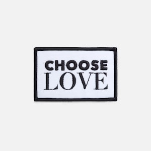 May include: A rectangular white patch with a black border. The words "CHOOSE LOVE" are embroidered in bold, black capital letters. The patch is a simple, yet impactful design.