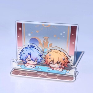 May include: A clear acrylic stand featuring two cartoon characters in a hot spring. One character has blue hair, the other has orange hair. The background depicts a landscape with a red and gold border. The text "jessehuanggg.bigcartel.com" is at the top.
