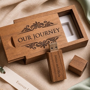 May include: A rectangular wooden USB flash drive box with a sliding lid engraved with the text OUR JOURNEY and decorative flourishes. A matching wooden USB drive engraved with James and Olivia and a separate cap sit beside a white tag reading Forever Loved.