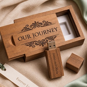 May include: A rectangular wooden USB flash drive box with a sliding lid engraved with the text OUR JOURNEY and decorative flourishes. A matching wooden USB drive engraved with James and Olivia and a separate cap sit beside a white tag reading Forever Loved.