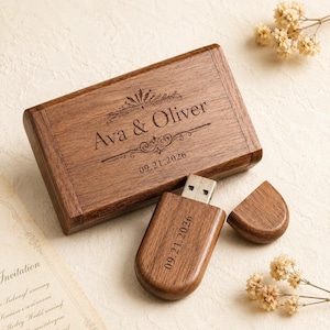 Puede incluir: Una caja rectangular de madera y una memoria USB a juego con tapa extraíble. La tapa de la caja está grabada con el texto Ava & Oliver y la fecha 09.21.2026. El cuerpo de la memoria USB también tiene grabada la fecha 09.21.2026 en tono oscuro.