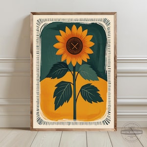 May include: A framed art print featuring a stylized sunflower. The sunflower has orange petals and a dark brown center with an 'X' mark. The background is divided into green and yellow sections, with a decorative border.