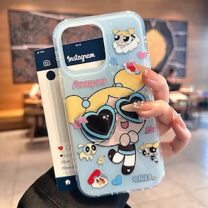 May include: A light blue phone case featuring a cartoon character with heart-shaped sunglasses and the text "Powerpuff". The case has a clear border and includes the Instagram logo.