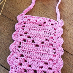 Peut inclure: Sac rose en crochet fait à la main, avec un bord festonné et une fermeture à bouton. Le sac a une sangle pour le porter et est fait d'un fil doux et texturé. Le sac mesure environ 18 cm de large et 20 cm de haut.