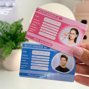 Könnte beinhalten: Zwei Relationship-ID-Karten, eine rosa und eine blaue, werden gezeigt. Die rosa Karte, mit der Aufschrift "Girlfriend", zeigt ein Foto und Details wie "Max 'Babe' Williams" und "Planning Date Nights". Die blaue Karte, mit der Aufschrift "Bovfriend", hat ähnliche Details.