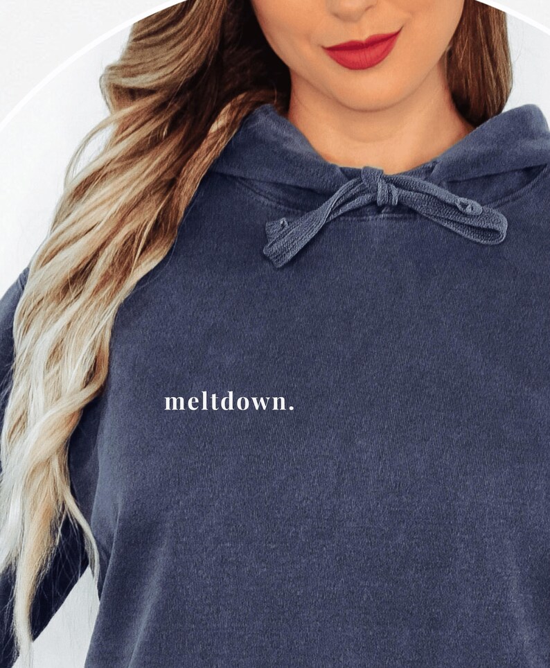Close-up of the front of the dark blue hoodie showing the word meltdown in small white lowercase letters on the right chest area.