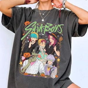 Könnte beinhalten: Dunkelgraues T-Shirt mit einem Halloween-Motiv und dem Text "SAIJA BOYS". Das Design zeigt Cartoon-Charaktere in Kostümen, darunter Vampire und eine Hexe, mit Kürbissen, Sternen und Fledermäusen. Das T-Shirt hat einen Vintage-Look.