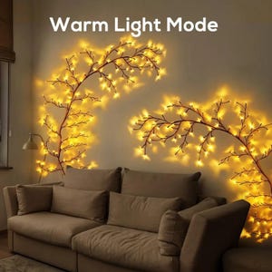 May include: A living room scene with a beige sofa and warm yellow string lights shaped like branches on the wall. The text "Warm Light Mode" is at the top. The lights create a cozy ambiance.