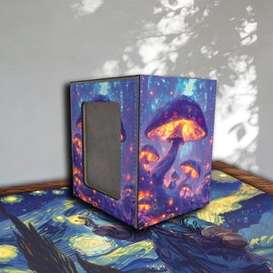 Peut inclure: Une boîte de rangement cubique avec un motif de champignons aux tons violets, bleus et oranges. La boîte a une ouverture rectangulaire sur un côté et est placée sur une surface avec une peinture de nuit étoilée.