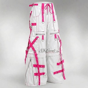 Könnte beinhalten: Weiße Hose mit weitem Bein und glänzender Oberfläche, ausgestattet mit leuchtend pinken Riemen, metallenen D-Ringen und mehreren Cargotaschen. Die Hose verfügt über einen Kordelzug in der Taille, silberne Reißverschlüsse und den Aufdruck UK Corset.