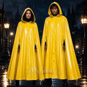 Puede incluir: Dos capas de lluvia amarillas brillantes a juego con capucha y cierre de botones frontal. Cada capa presenta una silueta larga y fluida con aberturas para los brazos y un acabado liso y reflectante. El texto UK Corset es visible en la parte inferior central.