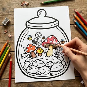May include: A black and white line drawing of a terrarium scene with mushrooms, bees, and plants. A person is coloring the image with a peach-colored pencil. Colored pencils and a pencil sharpener are scattered around the drawing.