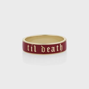 Puede incluir: Un anillo de oro con una banda ancha. La banda exterior es de color rojo oscuro con las palabras "til death" en una fuente gótica. Una joya sencilla pero audaz.