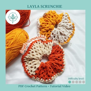 Puede incluir: Dos coleteros de ganchillo hechos a mano con un patrón de bloques de color en hilo crema y naranja quemado. Los coleteros se muestran junto a dos ovillos de hilo a juego. El texto en la imagen dice Layla Scrunchie y Drafterfly.
