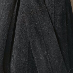 May include: Black elastic ribbon with a textured surface. The ribbon is folded and appears to be about 1 inch wide.