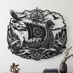 Könnte beinhalten: Ein Wandbild aus schwarzem Metall, das ein Wikingerschiff auf stürmischer See zeigt. Das Design umfasst einen Drachenkopf am Bug, ein Segel mit Vegvisir-Symbol, eine Kompassrose an der Spitze, fliegende Raben und stilisierte Blitze.