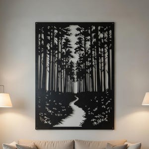 Puede incluir: Arte mural de metal negro que representa una escena de bosque con un camino sinuoso. La obra de arte está montada en una pared de color claro sobre un sofá beige. La habitación está decorada con lámparas y una mesa de centro de madera.