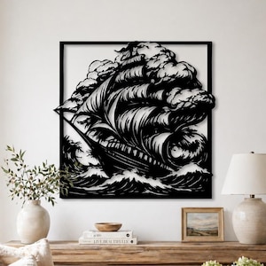 Op de afbeelding: Zwart metalen wandkunstwerk dat een zeilschip in een storm uitbeeldt. Het kunstwerk, omlijst in een zwart vierkant, toont het schip te midden van golven en wolken. Het is gemonteerd op een witte muur.