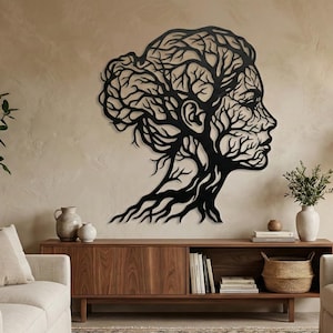 Könnte beinhalten: Schwarze Metall-Wandkunst, die das Profil einer Frau zeigt, wobei die Haare und der Hals aus Ästen gebildet werden. Das Kunstwerk ist an einer Wand in neutralen Tönen über einem Holzschrank angebracht.