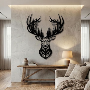Puede incluir: Una pieza de arte mural de metal negro con la cabeza de un ciervo. Las astas del ciervo están llenas de una silueta de bosque. La obra de arte está montada en una pared texturizada de color gris claro, creando un contraste llamativo. La cara del ciervo es detallada.