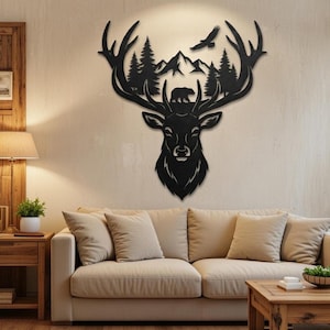Puede incluir: Arte mural de metal negro que representa una cabeza de ciervo con cuernos, montañas, árboles, un oso y un águila. La obra de arte está montada en una pared de color neutro sobre un sofá beige. La pieza añade un toque rústico a la habitación.