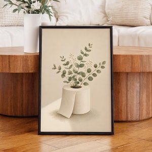 Pode incluir: Uma impressão de arte emoldurada com uma ilustração em aguarela de um rolo de papel higiénico branco que serve de vaso. Dentro do rolo estão ramos de eucalipto verdes com pequenas bagas brancas sobre um fundo bege claro.