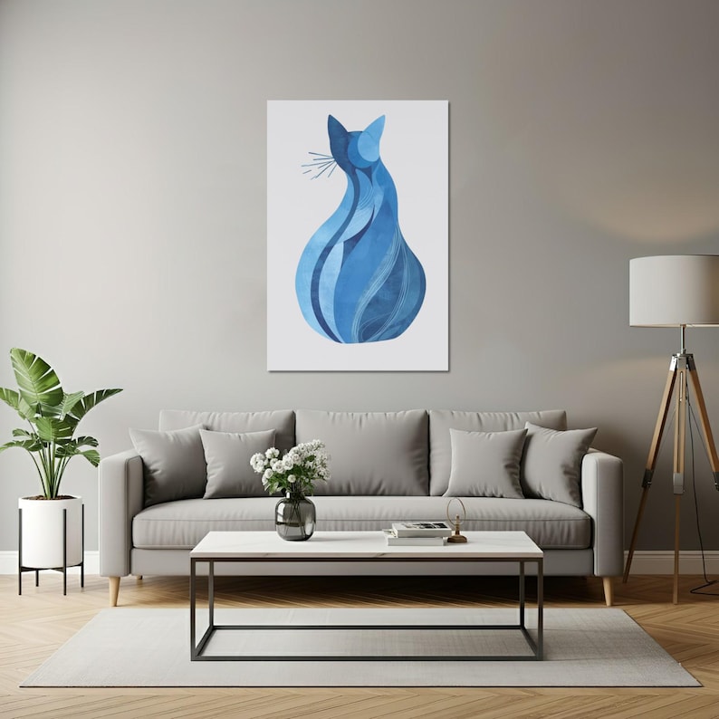 K&ouml;nnte beinhalten: Blauer abstrakter Katzenkunstdruck auf wei&szlig;em Hintergrund. Das Kunstwerk zeigt eine stilisierte Katzensilhouette mit flie&szlig;enden Linien und verschiedenen Blaut&ouml;nen. Der Druck wird &uuml;ber einem grauen Sofa in einem Wohnzimmer gezeigt.
