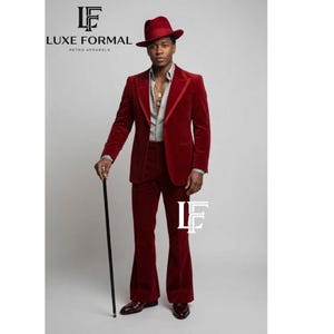 May include: A burgundy velvet suit with a matching fedora hat. The suit features a tailored blazer and flared pants. The person is holding a black cane. The logo "LUXE FORMAL RETRO APPARELS" is visible in the upper left and lower right corners.