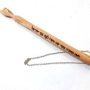 May include: A wooden yad with a carved hand at the top and a silver chain attached to the bottom. The yad is inscribed with Hebrew text.