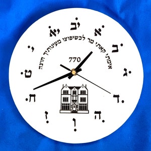 Puede incluir: Reloj redondo blanco con agujas negras y texto hebreo negro alrededor del borde. El texto dice "אימתי קאתי מר לכשיפוצו מעינותיך חוצה" y "770".
