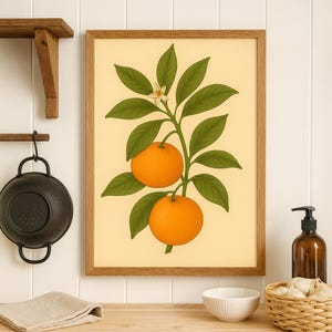 May include: A framed botanical print featuring two bright orange oranges on a branch with green leaves and a small white flower. The artwork is set against a pale yellow background and framed in a light brown wooden frame. The print is a kitchen or dining room wall decor.