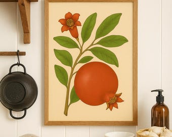 May include: A framed botanical print featuring a pomegranate branch with a large, ripe fruit and green leaves. The artwork includes a red flower and a smaller pomegranate bud. The print is set against a cream-colored background and framed in light brown wood.