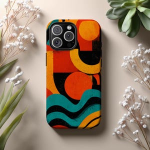 Op de afbeelding: Een kleurrijke telefoonhoes met een abstract ontwerp. De hoes heeft een levendig patroon van oranje, gele, zwarte en turquoise vormen. Het ontwerp omvat cirkels, vierkanten en golvende lijnen, waardoor een retro, geometrische esthetiek ontstaat.