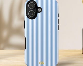 May include: A blue and white striped phone case featuring a dual-lens camera. The case has black side buttons and gold initials "SS" at the bottom. The case is on a wooden surface.