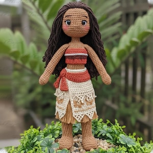 May include: A handmade crochet doll with dark brown hair and a tan complexion. The doll wears a red and brown top, a cream-colored skirt with brown floral accents, and a matching red sash. The doll is approximately 12 inches tall.