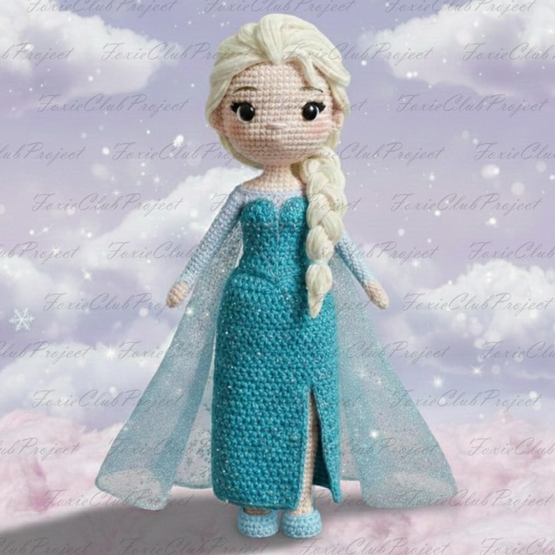 May include: A handmade crochet doll of a character with blonde hair in a side braid. The doll wears a turquoise dress with a slit and a sheer cape. The doll's face has embroidered features and is wearing blue shoes. The doll is approximately 10 inches tall.