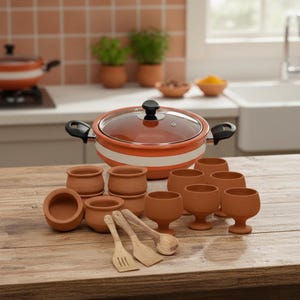 May include: A terracotta cooking pot with a glass lid, white stripes, and black handles, surrounded by small terracotta cups, bowls, and wooden utensils. The set is displayed on a wooden surface.