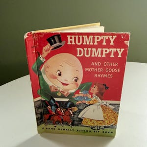 Puede incluir: Libro vintage "Humpty Dumpty and Other Mother Goose Rhymes". La portada roja tiene el título en blanco. La ilustración muestra a Humpty Dumpty, una niña y soldados a caballo. Un libro Rand McNally Junior Elf.