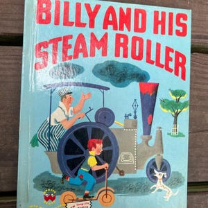 May include: A vintage children's book cover with a blue background featuring a red and gray steamroller with a man and a boy riding on it. The book title is "Billy and His Steam Roller" with the words "New Long-life Binding" at the bottom.